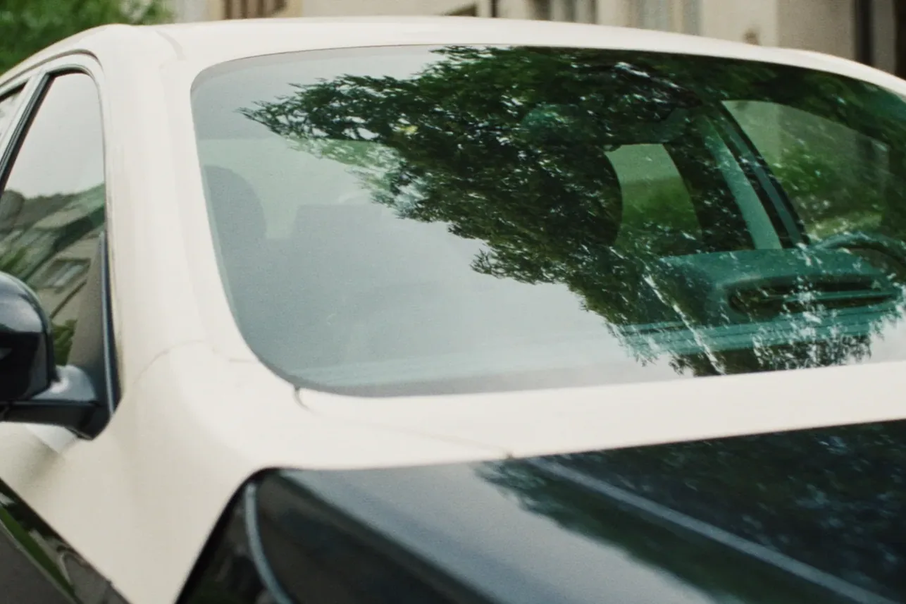 A freshly installed windshield on a parked car, clean and clear from the outside